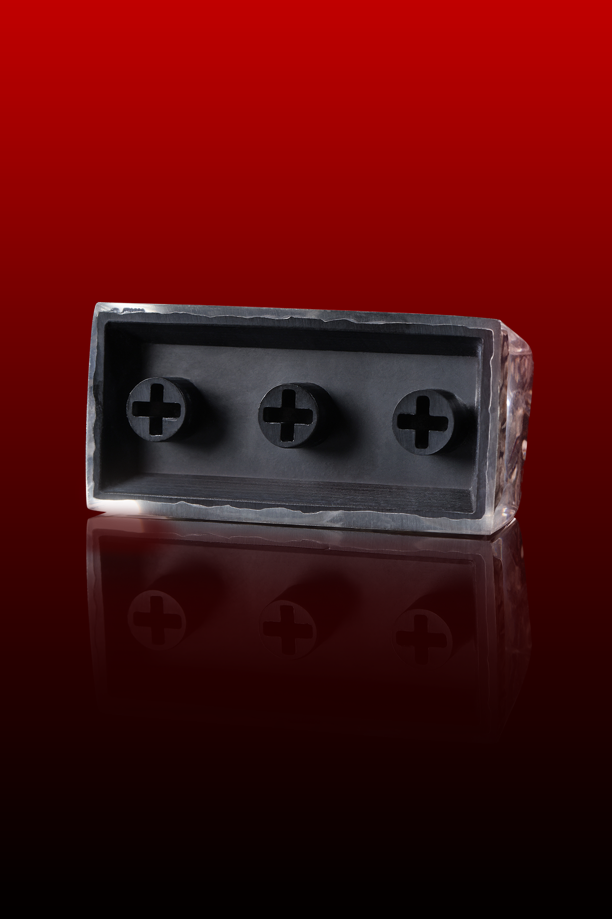 Metallic block with circular cutouts on a reflective red surface