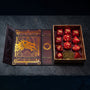 The dice set inside its open box. This purple-red box features gold foil artwork feat. the Ebonheart dragon head, the game’s three-headed Ouroboros, and dragon tongue writing.